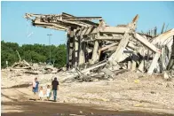  ?? David Guralnick/Detroit News via AP ?? ■ A family walks past the rubble that was once the Palace of Auburn Hills, which underwent a controlled demolition Saturday in Auburn Hills, Mich. Opened in 1988, the multi-use stadium was the home of the Detroit Pistons as well as numerous concerts and sporting events.