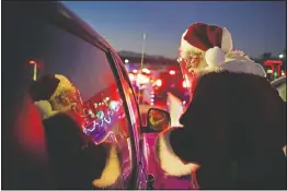  ?? (AP/John Locher) ?? Charlie Bush, dressed as Santa Claus, wears a face shield as a precaution against coronaviru­s as he greets people waiting in their cars at Glittering Lights, a drive-through holiday lights display in Las Vegas.