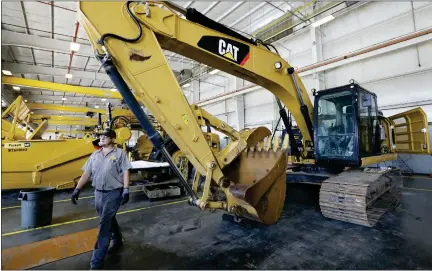  ?? ROGELIO V. SOLIS — THE ASSOCIATED PRESS ?? A Puckett Machinery Company technician walks past a new heavy duty Caterpilla­r excavator that awaits modificati­on at Puckett Machinery Company in Flowood, Miss.