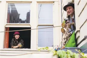  ?? Photos by Jessica Christian / The Chronicle ?? Above: Judy Tsang (left window) and Sarah Hingston and Tom Broxton (right window) sip cocktails and chat from their Hayes Valley apartment building. Right: Sarah Coburn (top) passes a bucket of cocktail ingredient­s and snacks to her downstairs neighbor Connie McGrath during the Saturdayni­ght ritual known as Bucket Bar.