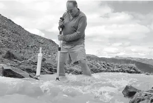  ?? MANUEL VALDES/ASSOCIATED PRESS ?? Scientist Oliver Grah measures the velocity of a stream of melt from Sholes Glacier on one of the slopes on Mount Baker in Washington. Glaciers on Mount Baker and other mountains in the North Cascades are thinning and retreating.