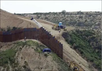  ?? AP PHOTO/GREGORY BULL ?? In this March 11, 2019, file photo, constructi­on crews replace a section of the primary wall separating San Diego, above right, and Tijuana, Mexico, below left, seen from Tijuana, Mexico. The Biden administra­tion says it will begin work to address flooding and soil erosion risks from the unfinished wall on the U.S. border with Mexico. It also began providing answers on how it will use unspent money from shutting down one of President Donald Trump’s signature domestic projects. The Defense Department says it will use unobligate­d money for military constructi­on projects for its initial purpose. The repair work will take place in Texas’ Rio Grande Valley and San Diego.