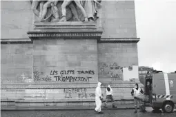  ??  ?? AFTERMATH – Workers start to clean up debris and other trash left by rallyists at the foot of the one of the Arc de Triomphe’s columns heavily vandalized after a wave of protests in Paris, France. (AP)