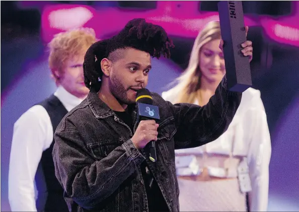  ?? — PHOTOS: THE CANADIAN PRESS ?? Toronto crooner The Weeknd picks up one of his three prizes — best pop video — at the Much Music Video Awards in Toronto on Sunday. MMVA co-host and British singer Ed Sheeran was the evening’s only other multiple winner.