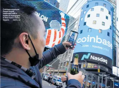  ?? PHOTO /AP ?? Coinbase employee Daniel Huynh celebrates with a bottle of champagne in New York’s Times Square.