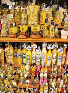  ??  ?? Galben de soare: Sticlele de limoncello se găsesc sub toate formele pe Via Roma, mărginită de magazine, din orașul Capri; pe coastă se adună iahturile și bărcile cu pânze (alături).