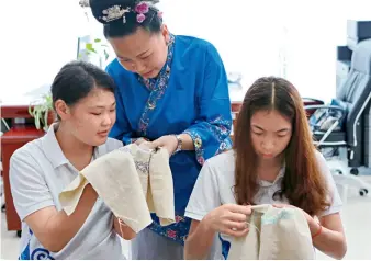  ??  ?? Le 30 juin 2016, une artisane de l’Institut profession­nel de Tangrenfan­g pour le patrimoine culturel immatériel, dans le district de Huishui (Guizhou), enseigne aux élèves le batik, le tissage et la broderie.