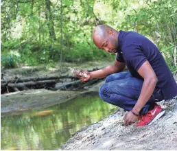  ?? PHOTOS BY SHONDIIN SILVERSMIT­H/USA TODAY NETWORK ?? Evan Lewis takes rocks from the Mill Shoal Creek bed as mementos from where his family lived.