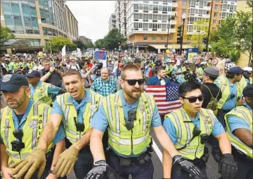  ?? Nicholas Kamm AFP/Getty Images ?? POLICE ESCORT far-right marchers, including neo-Nazis, at Lafayette Park near the White House on Aug. 12. The website Daily Stormer has grown in prominence while neo-Nazi activity has become more visible.