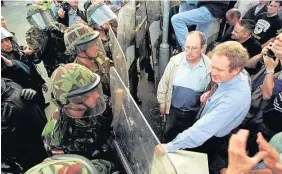  ??  ?? > Sinn Fein’s Martin McGuinness faces British troops in Bellaghy, July 1997