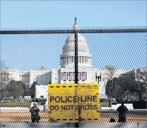  ?? SHAFKAT ANOWAR/AP ?? National Guard members stand Wednesday behind a fence that was erected to reinforce security at the Capitol in Washington, D.C.