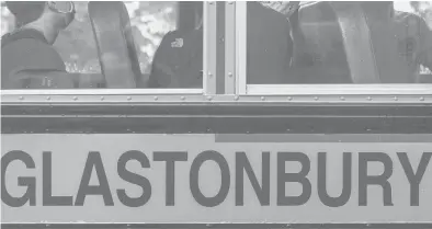  ?? MARK MIRKO/HARTFORD COURANT ?? Students, wearing their required masks and sitting socially distanced, arrive on campus by bus for the first day of classes at Glastonbur­y High School in August 2020.