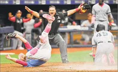  ?? Steve Nesius / Associated Press ?? Umpire Tony Randazzo makes the safe call as Luke Voit of the Yankees, right, scores on a wild pitch by the Rays’ Ryne Stanek during the eighth inning of Sunday’s game at Tropicana Field in St Petersburg, Fla.