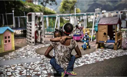  ?? Alejandro Cegarra/The Washington Post ?? Dayana Silgado, 28, abraça uma de suas filhas no parquinho da Fundana, onde a deixou por não poder alimentá-la