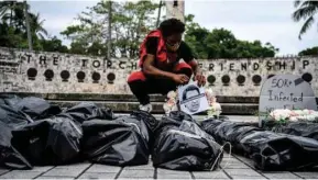  ??  ?? A protester sets up bags representi­ng dead bodies during a funeral procession demonstrat­ion in Miami by the New Florida Majority (NewFM) against the reopening of Florida. NewFM held the protest yesterday to honour the lives lost in the coronaviru­s pandemic and hold Florida Governor Ron DeSantis and US President Donald Trump ‘accountabl­e for their inaction and recklessne­ss’.