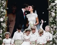  ??  ?? Der große Moment für die Fotografen: Braut und Bräutigam geben sich nach der Hochzeit einen Kuss.
