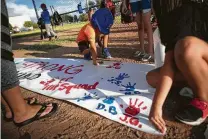  ??  ?? Xsquad baseball player Ian Chavez, 6, puts his handprint on a banner for a makeshift memorial honoring the victims.