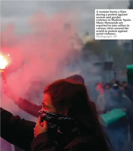  ?? Photograph: AP ?? A woman burns a flare during a protest against sexism and gender violence in Madrid, Spain. Many thousands are expected to join rallies in various cities around the world to protest against sexist violence.