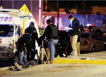  ?? — Reuters photo ?? Members of the forensic team work at a crime scene where according to local media two men and a woman were killed when gunmen opened fire on Saturday at a street in Ciudad Juarez, Mexico.