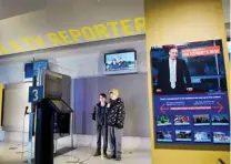  ??  ?? Two teenagers read a news report from a teleprompt­er and see themselves in action at the “Be a TV Reporter” station at the Newseum.