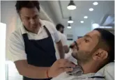  ?? — AFP ?? A male hairdresse­r trimming a customer’s beard at a men’s salon in Islamabad.