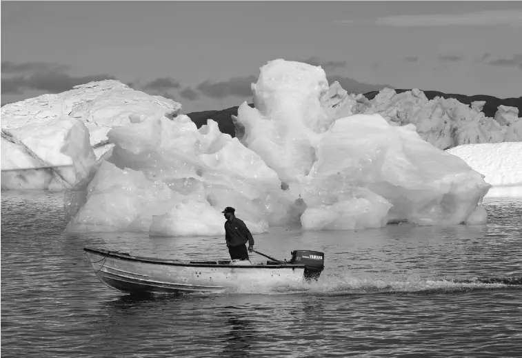  ?? ANDREW TESTA/ NEW YORK TIMES ?? A fisherman sails past melting icebergs in Narsaq, Greenland. As warming temperatur­es upend traditiona­l life, they are also offering up intriguing new opportunit­ies for a lucrative mining economy.