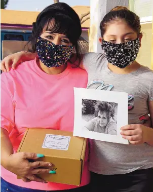  ?? ADOLPHE PIERRE-LOUIS/JOURNAL ?? Mariaelena Lopez, left, holds the cremated remains of her mother, Maxine Roybal Lopez. Mariaelena Lopez’s niece Alexsa Lopez, 10, holds a photograph of Roybal Lopez.