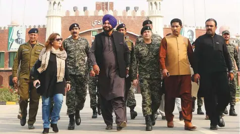  ?? AFP ?? India’s Punjab cabinet minister and former cricketer Sidhu (fourth from left) entering Pakistan at the border crossing in Wagah yesterday. Sidhu will attend the groundbrea­king ceremony of the Kartarpur Corridor scheduled for today.