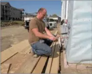  ??  ?? Above, John Mizell, a technician for an Arkansas air conditioni­ng contractor, tapes some piping at an apartment constructi­on site in northeast Bismarck, N.D. At right, a constructi­on worker signals to the driver of a forklift who is lifting...