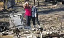  ??  ?? DEE PALLESEN, left, and daughter Emily Learn take in the rubble of Pallesen’s home. Eight people were killed in the fire.