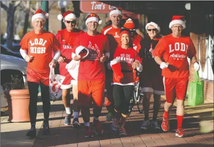  ?? BEA AHBECK/NEWS-SENTINEL ?? Lodi High “Running Santas” Shawn Allen, Bob Whittaker, Matt Hayward, Robert Winterhalt­er, Lynette Haley, Mike Wood and Jud Atwater make the rounds at Downtown businesses on Friday.