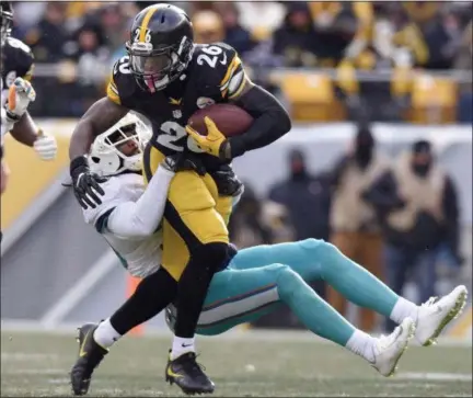  ?? DON WRIGHT — THE ASSOCIATED PRESS ?? Pittsburgh Steelers running back Le’Veon Bell (26) runs through a tackle by Miami Dolphins free safety Bacarri Rambo during the first half of an AFC wild-card NFL football game in Pittsburgh, Sunday.