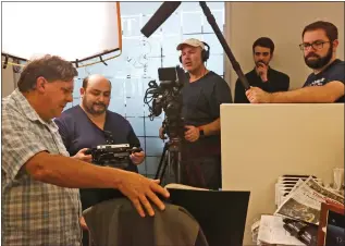  ?? Photo by Katharine Lotze/The Signal ?? Signal senior reporter Jim Holt shows archive copies of the Signal to a French film crew, showing stories about the Paul Walker and Roger Rodas crash in November 2013.