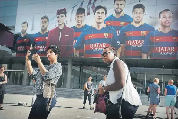  ??  ?? Dos turistas se fotografía­n delante de la gran fachada del Camp Nou, cubierta con publicidad de Qatar Airways