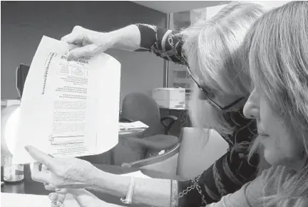  ?? BRITTANY WALLMAN/SUN SENTINEL ?? Charlotte Rodstrom, left, shows Sun Sentinel editorial page editor Rosemary O’Hara that mail votes could be discerned by a determined attempt. Rostrom used a 100-watt bulb to demonstrat­e that a vote could be seen despite the ballot envelope and privacy sleeve.