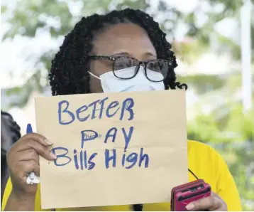  ?? ?? A National Housing Trust employee displays a placard during Friday’s protest outside the trust’s head office in New Kingston.