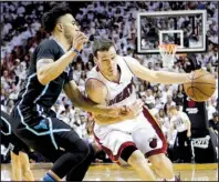  ?? AP/ ALAN DIAZ ?? Miami guard Goran Dragic ( right) looks for room around Charlotte defender Courtney Lee in Game 7 of their NBA playoff series Sunday. Dragic had 25 points to push the Heat past the Hornets 106- 73 and into the Eastern Conference semifi nals.
