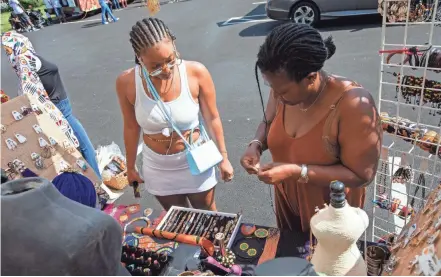  ?? PHOTOS BY NICOLAS GALINDO/COLUMBUS DISPATCH ?? Nyasia Crandall, left, looks for jewelry with help from Astrid Coffi, owner of Coffi Co. African Beauty and Fashion, during the Columbus African Festival at Franklin Park in Columbus on Saturday. “I thought the jewelry was really nice,” Crandall said. “I grabbed some for me and my boo.”