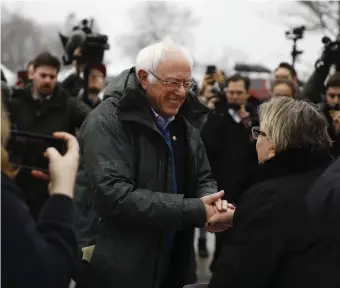 ?? AP ?? ‘FIRST CHOICE SINCE LAST TIME’: Democratic presidenti­al candidate Sen. Bernie Sanders meets with people outside a polling place in Manchester, N.H., on Tuesday. Opposite page, a Sanders supporter holds a sign and his dog in Manchester.