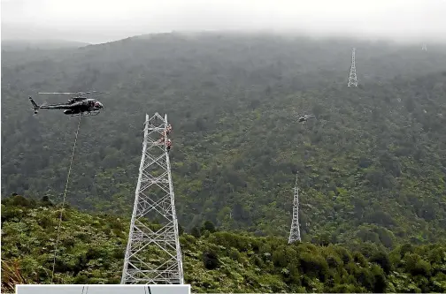  ??  ?? A Blackhawk helicopter lifts the final section on to a transmissi­on tower at Mercury’s Turitea wind farm. A smaller Squirrel helicopter delivers components in the background.