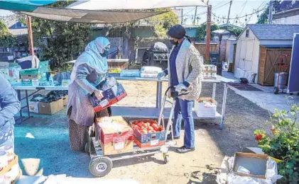  ?? EDUARDO CONTRERAS U-T PHOTOS ?? Katherine Bom (right), executive director of RefugeeNet and a former refugee herself, helps refugee Mouna Mohamed collect food and supplies during a food drive at St. Luke’s Episcopal Church in San Diego.