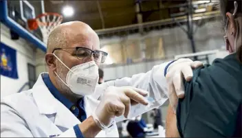  ?? CHRISTOPHE­R DOLAN / THE TIMES-TRIBUNE ?? University of Scranton nursing student Glen Johnson administer­s the Moderna COVID-19 vaccine to a medical profession­al during a clinic at the Throop Civic Center in Throop, Pa., on Saturday.