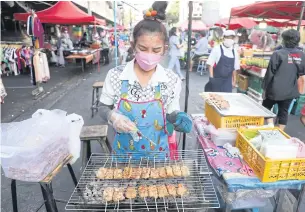  ?? NUTTHAWAT WICHEANBUT ?? A vendor grills skewered pork in Bangkok. The hike in pork prices forced her to raise her price to seven baht a skewer from five baht, which turned customers away. She then cut the price to six baht.