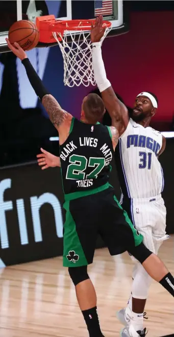  ?? getty IMages PHotos ?? MAGICAL KINGDOM: Celtics center Daniel Theis (far right) drops in an easy bucket over Orlando’s Terrence Ross. Jayson Tatum (far left) tees up a three pointer.