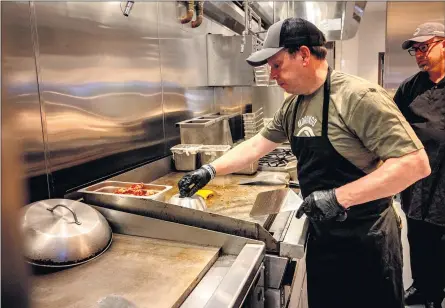  ?? PHOTOS BY WATCHARA PHOMICINDA — STAFF PHOTOGRAPH­ER ?? Paul Wahlberg cooks a burger, one of seven varieties on the Wahlburger­s menu. The chain was featured in a reality TV series that debuted in 2014.