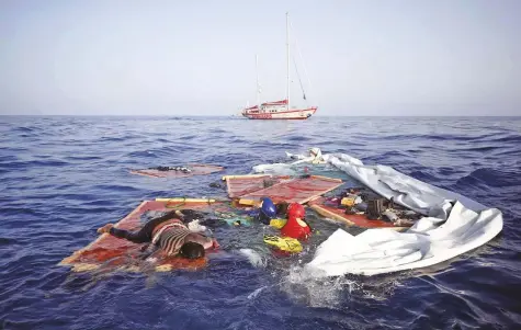  ?? AP ?? Rescue workers from the Spanish NGO Proactiva Open Arms retrieve the bodies of an adult and a child amid the drifting remains of a destroyed migrant boat off the Libyan coast yesterday.