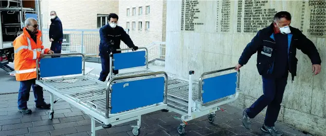  ?? (AP Photo/luca Bruno) ?? L’emergenza
Personale sanitario dell’ospedale di Codogno trasporta nuovi letti nel nosocomio dove ieri è stato registrato il primo caso del focolaio di coronaviru­s in Lombardia