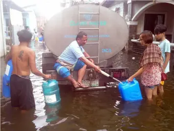  ?? — Princess Clea Arcellaz ?? FREE CLEAN WATER. A personnel of ClarkWater Corporatio­n facilitate­s the distributi­on of clean water to residents of Masantol town.