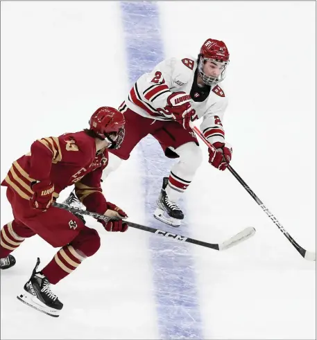 ?? PHOTOS BY MARK STOCKWELL — BOSTON HERALD ?? Boston College’s Cutter Gauthier (19) and Harvard’s Sean Farrell (21) chase the puck during the first period of the Beanpot men’s hockey semifinal at TD Garden.