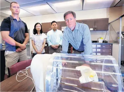  ?? JOE BURBANK/STAFF PHOTOGRAPH­ER ?? Rodney Bosley Jr., CEO of SegAna, Inc. displays a digitally-printed lung, foreground, with grad student Jeff Colton, left; Dr. Jan Gou, a University of Central Florida engineerin­g professor; and grad student Xin Wang Gou’s lab on campus Friday.